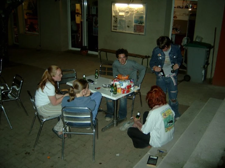 four people sitting at tables talking to one another