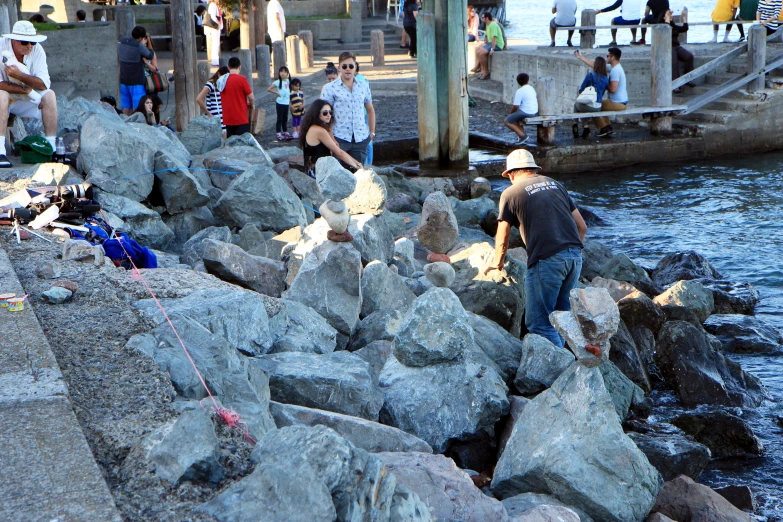 group of people standing by rocks next to a body of water