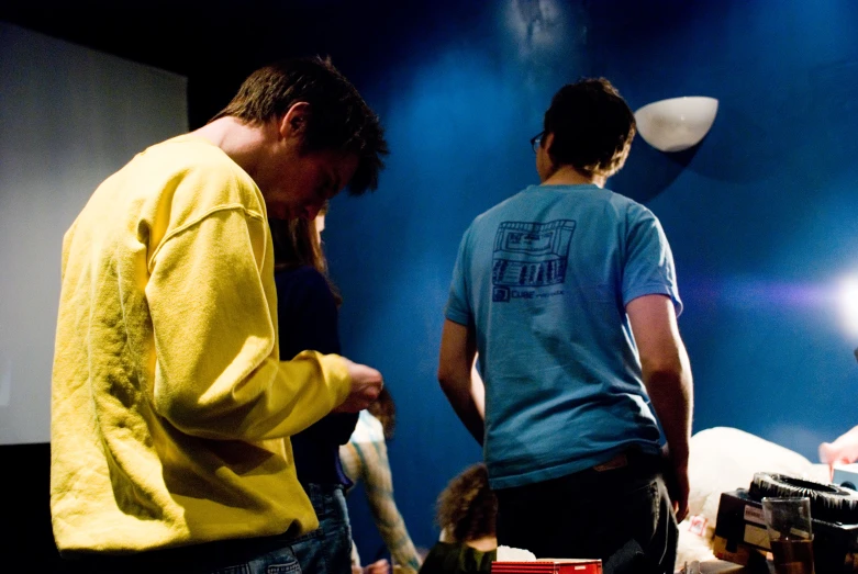 two men are standing in a dark room with a small table