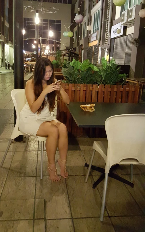 a woman sitting on a white chair outside at night