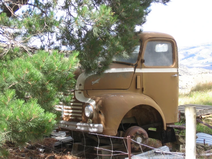 an old rusted truck sits on the side of the road
