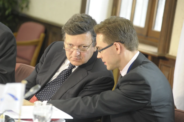 a man sitting next to another man at a table