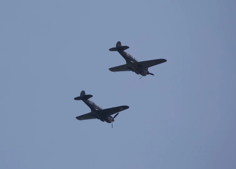 two small planes fly in the sky close together