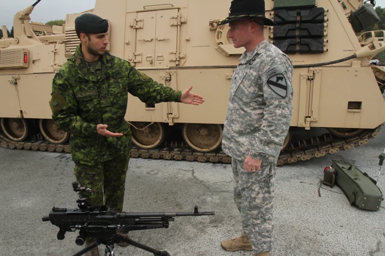 two soldiers in camouflage talk to each other