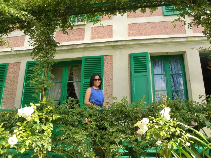 a woman in blue shirt standing in front of green windows