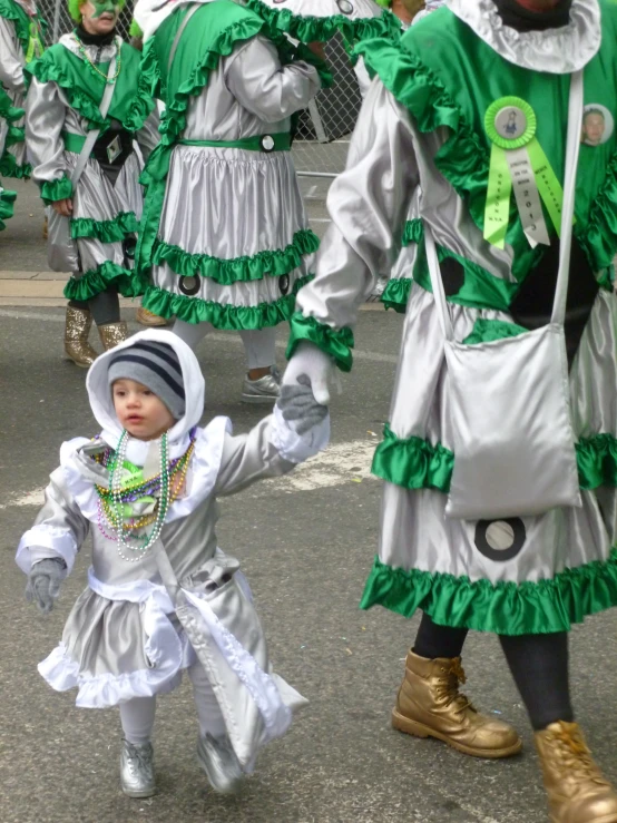 a man wearing a green dress holding a little girl