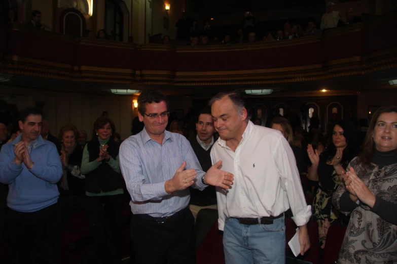 two men and a woman standing on a stage clapping