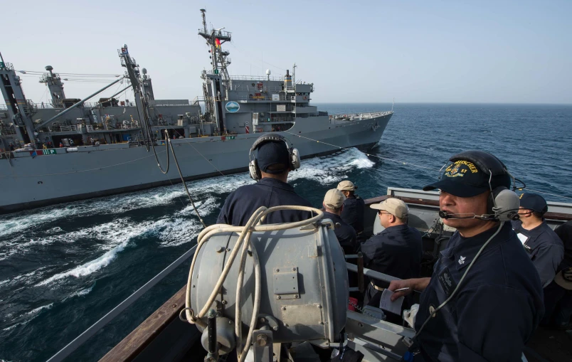 several men in blue jackets standing on the deck of a boat