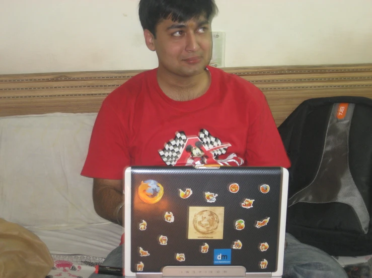 a young man sitting in a bed while using a laptop