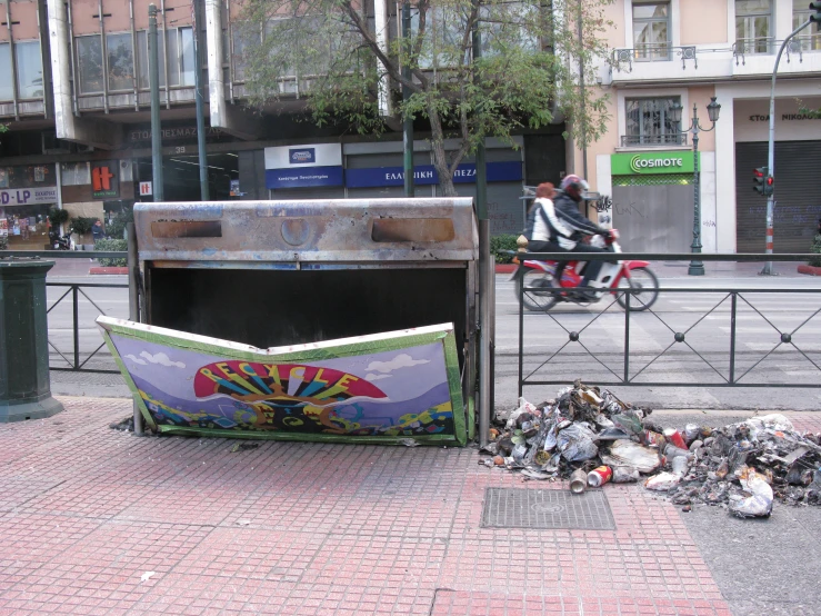 an open trash bin is near a street