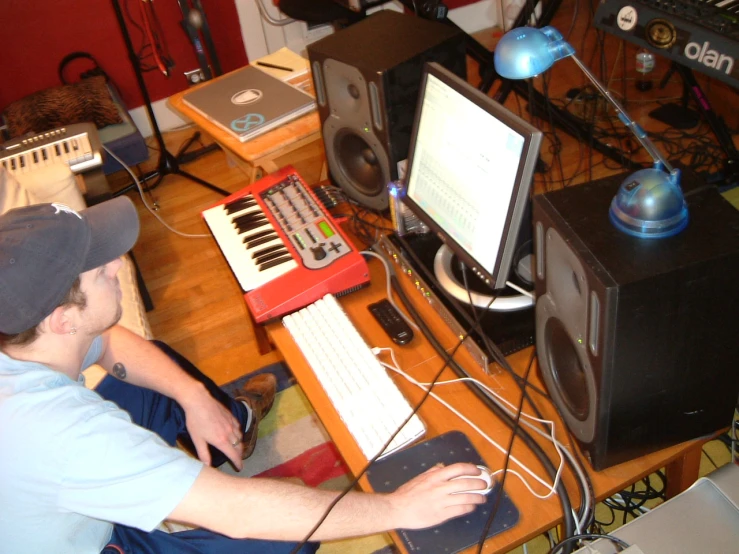 a guy sitting at his computer keyboard playing a song