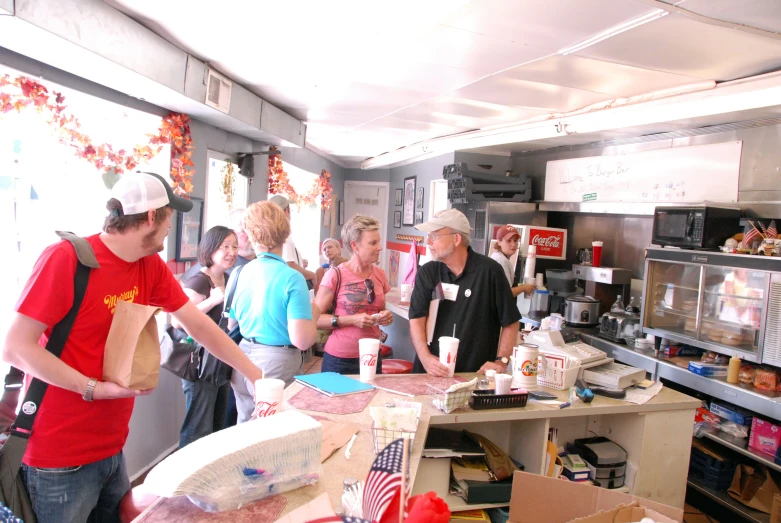 several people wait around the counter in a food shop