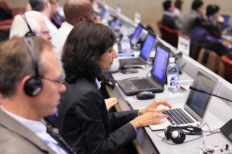 a group of people sitting at desk working on laptops