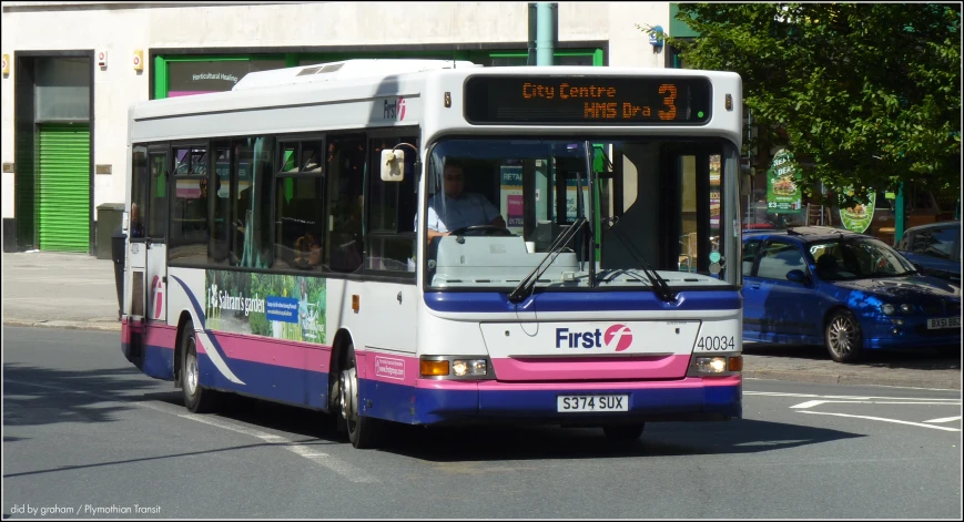 a white, purple, and black bus driving on a road
