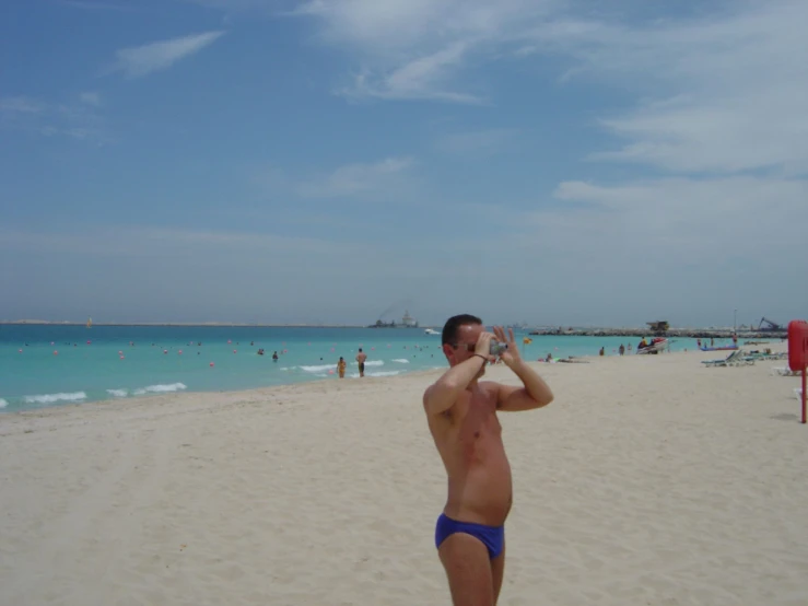 a man taking a picture on the beach with his cellphone