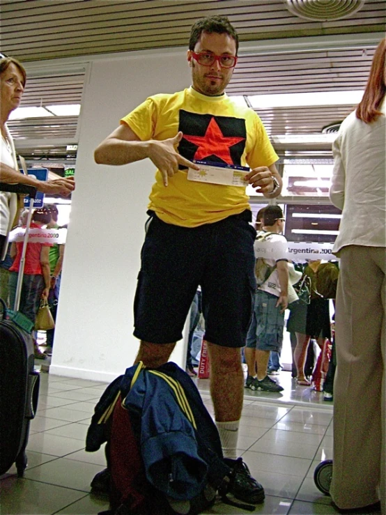 a man wearing an star and flag t - shirt stands in the airport