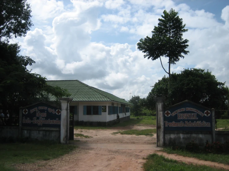 two large white houses with blue sign and trees on each