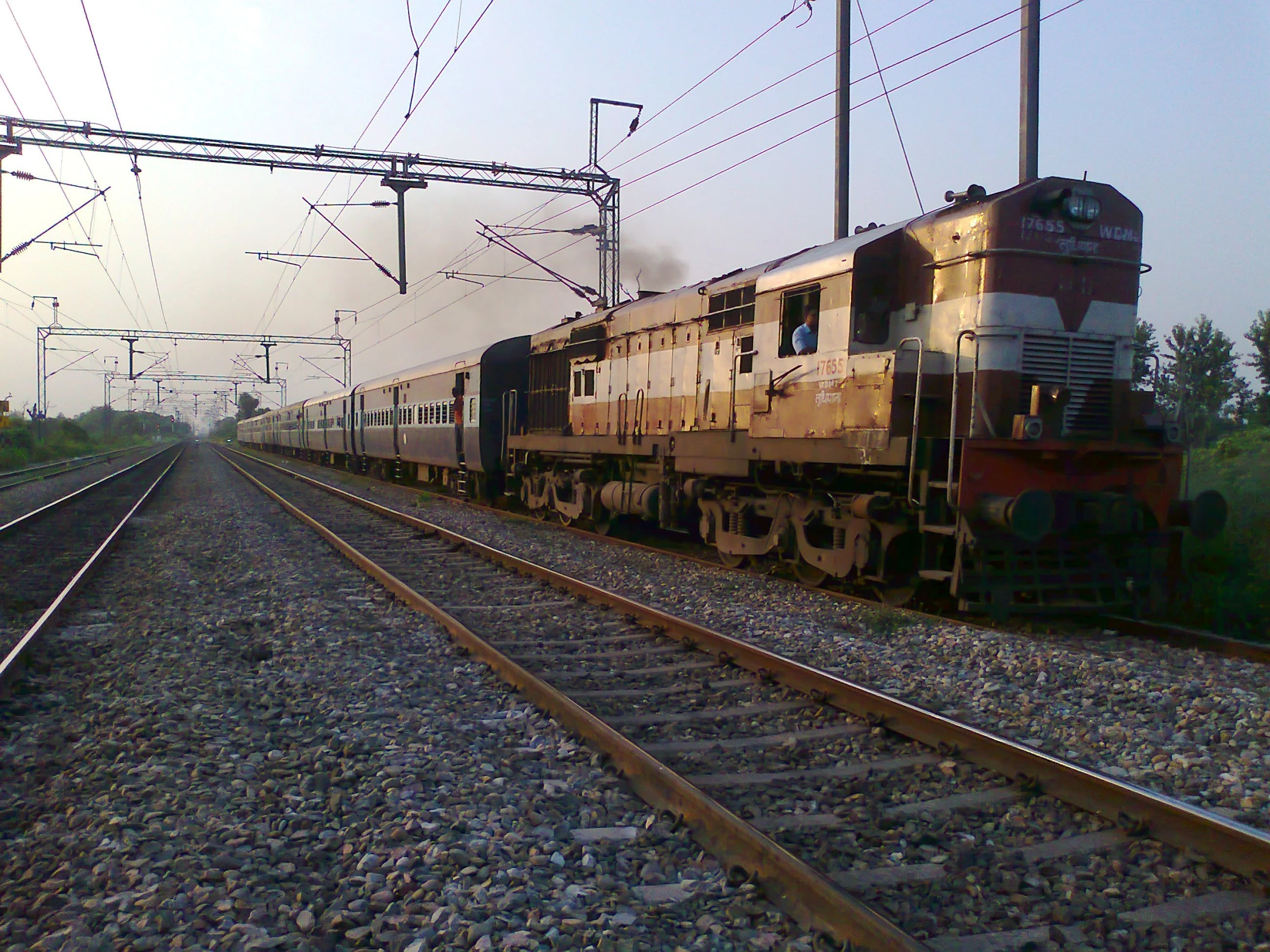 an amtrak train moves down the tracks as the sun is going down