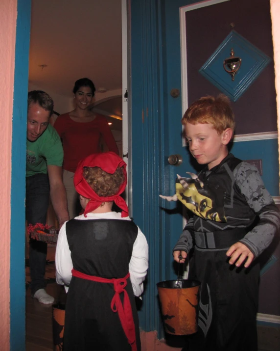 two children standing in front of a door wearing pirate costumes