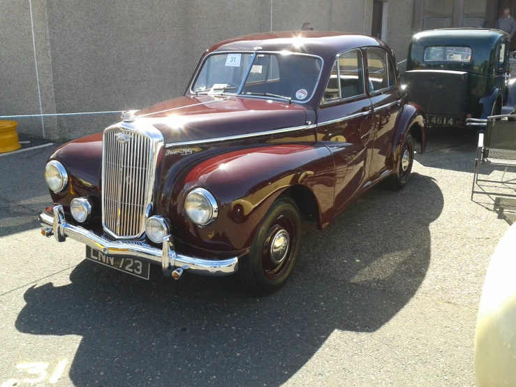 an old, maroon car parked in front of a building