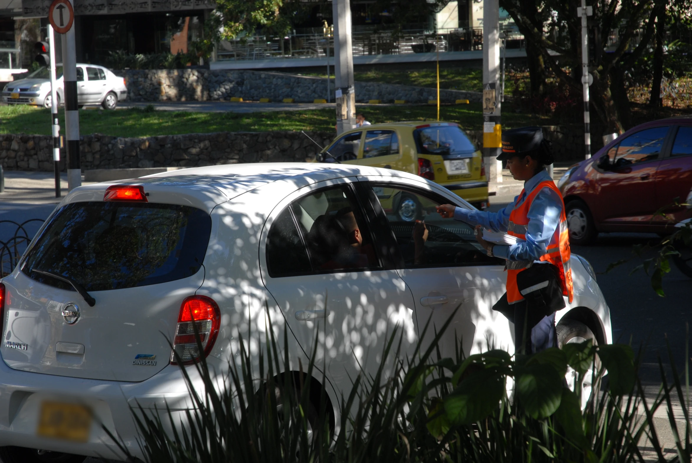 a man standing next to a white car at a stop sign