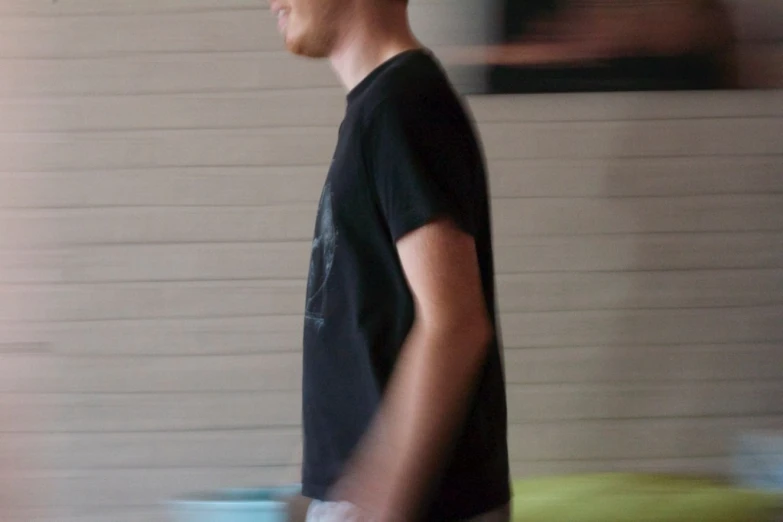 a man in black shirt and red hat walking past wall