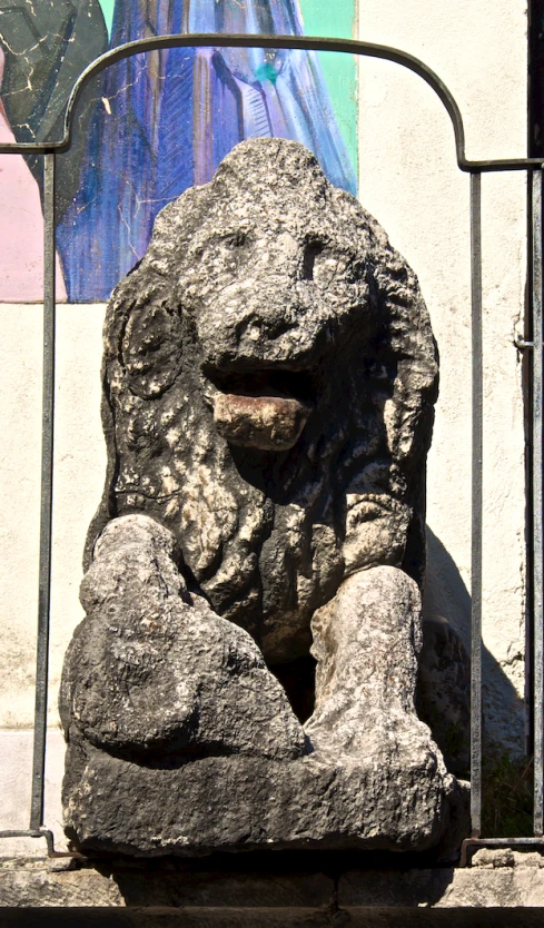 a large stone face sculpture behind bars on a gate