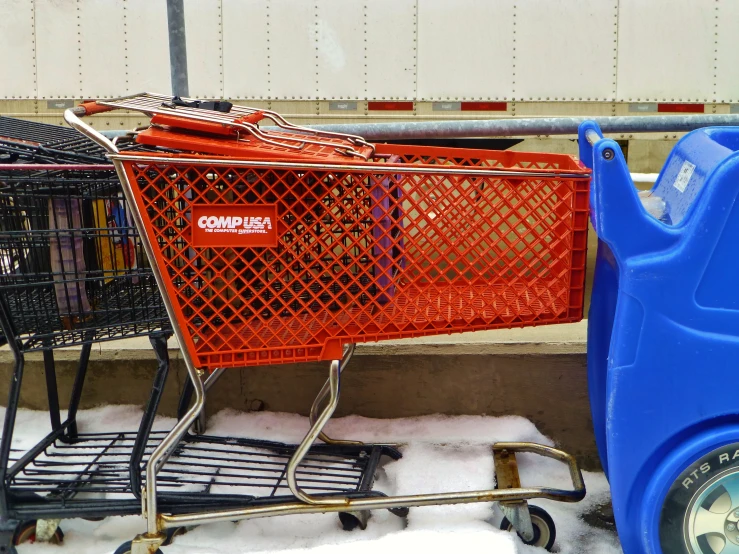 two shopping carts, one blue and one red, are piled on snow