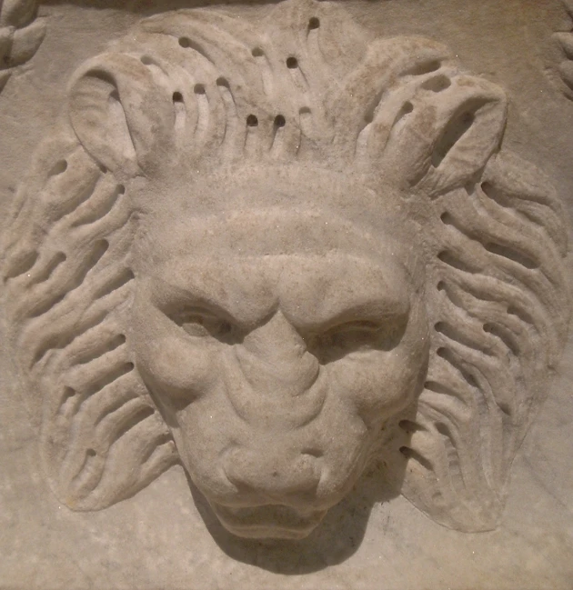 a stone lion face next to a window