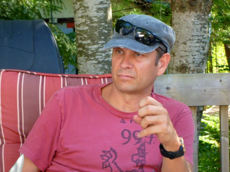 a man wearing a hat and sunglasses sitting on a red chair