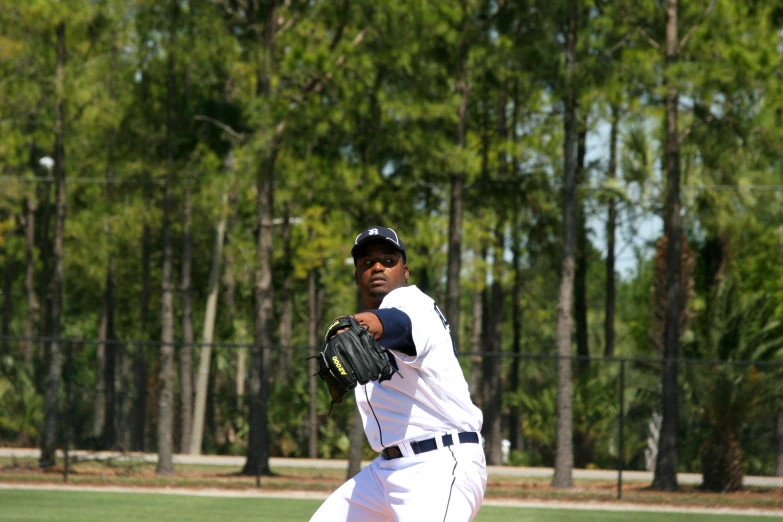 man wearing white uniform throwing baseball in open field