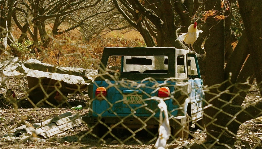 an old blue truck behind a chain link fence