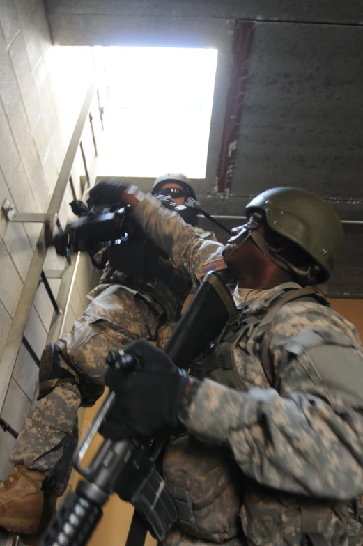 two men in uniforms with guns laying on top of each other