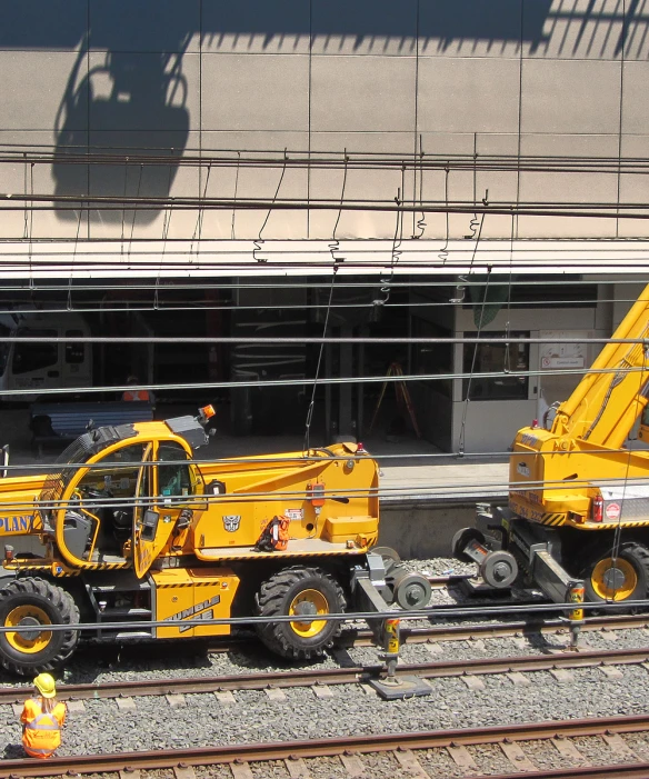 two big yellow construction machines in front of a building