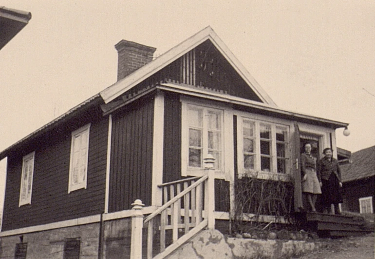 a man and a woman standing on the porch of a black and white house