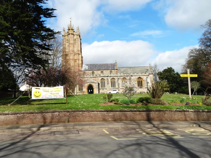a road view of a church with a sign on the grass