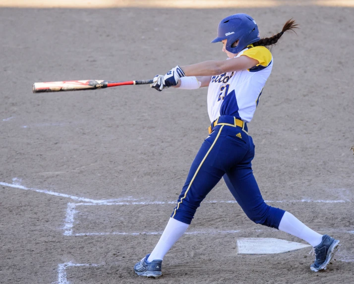 a woman swinging a baseball bat on top of a field