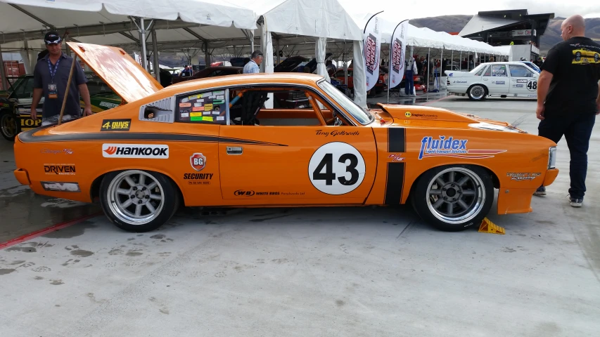 the orange muscle car is parked at the garage