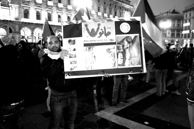 a man holding up an old poster with posters on it