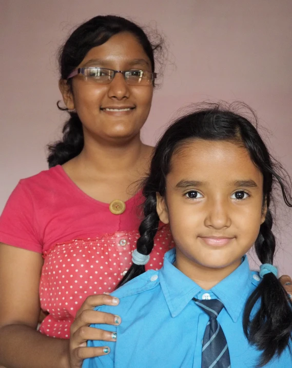 a girl with glasses stands beside her mother