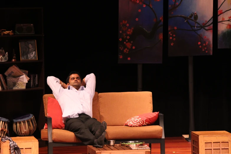 a man on a couch in a room with a shelf