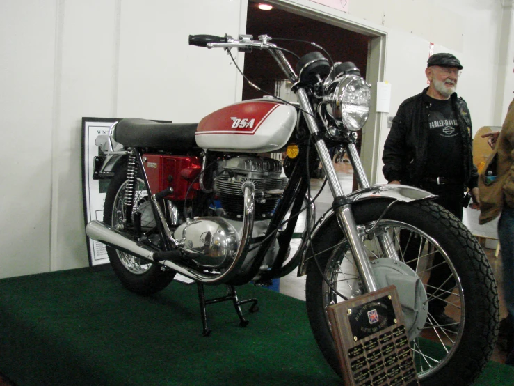 two men looking at a parked motor bike