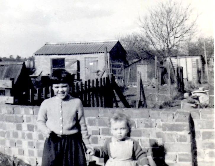 a vintage po of two children next to a brick wall