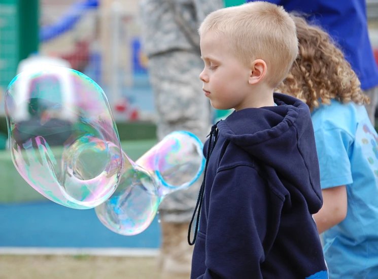 the boy is holding soap bubbles near other children