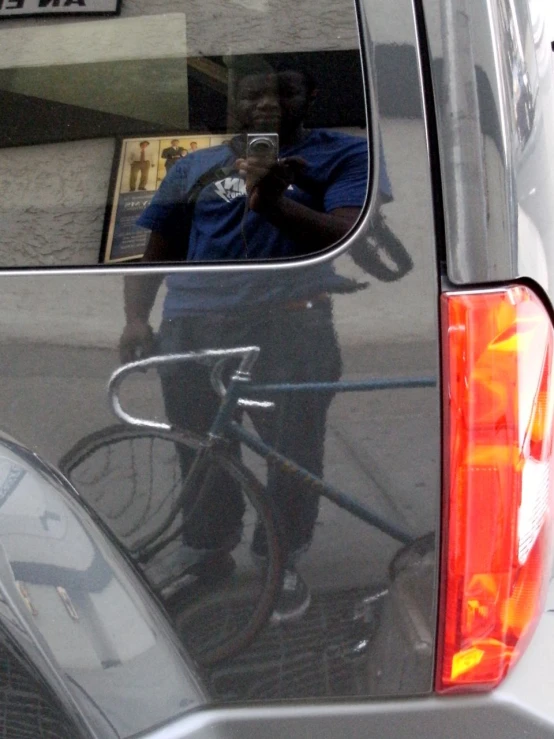 a man standing on his bicycle looking at the car mirror