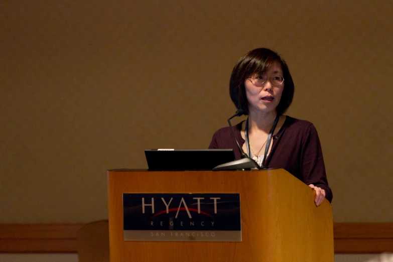 a woman with a microphone stands behind a podium