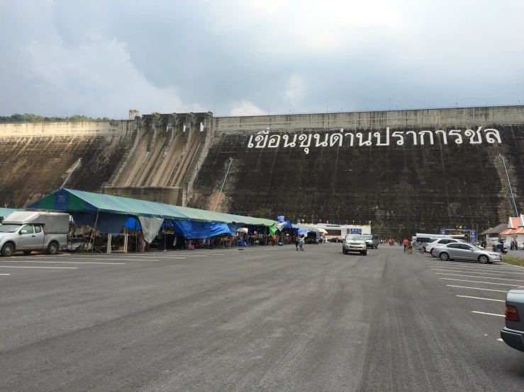 a concrete wall next to a road with many parked cars