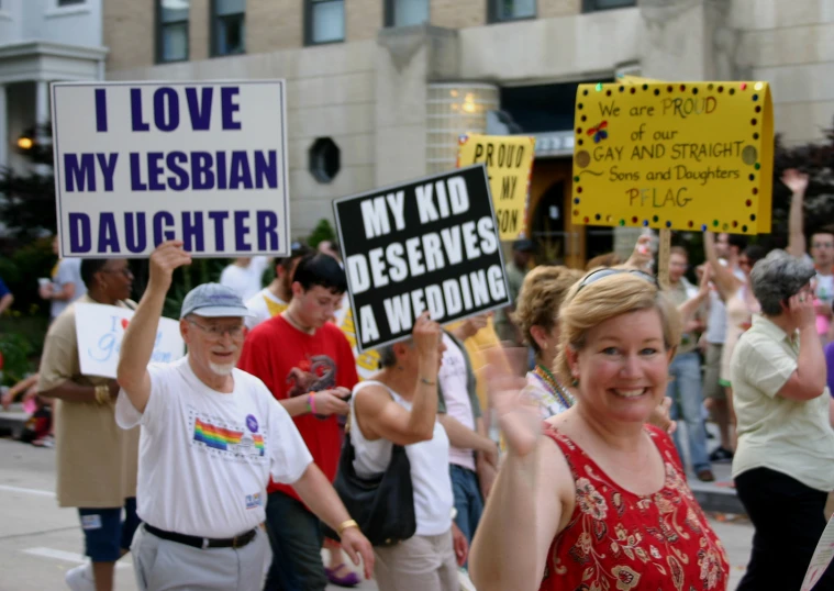 a group of people are holding signs on the side of the street