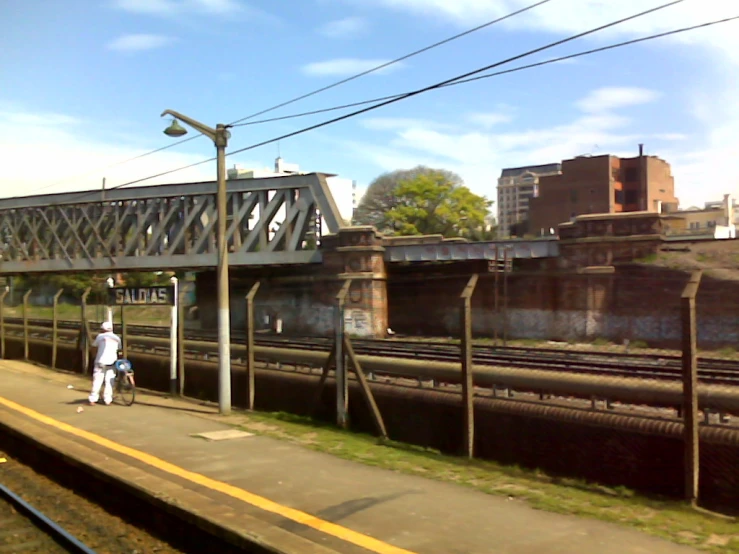 some people are walking along the side of a rail road bridge