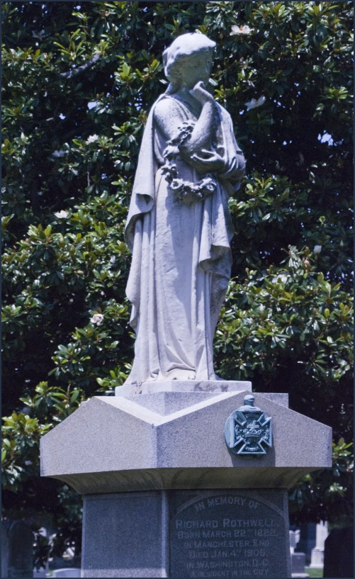 a statue in front of some trees and bushes